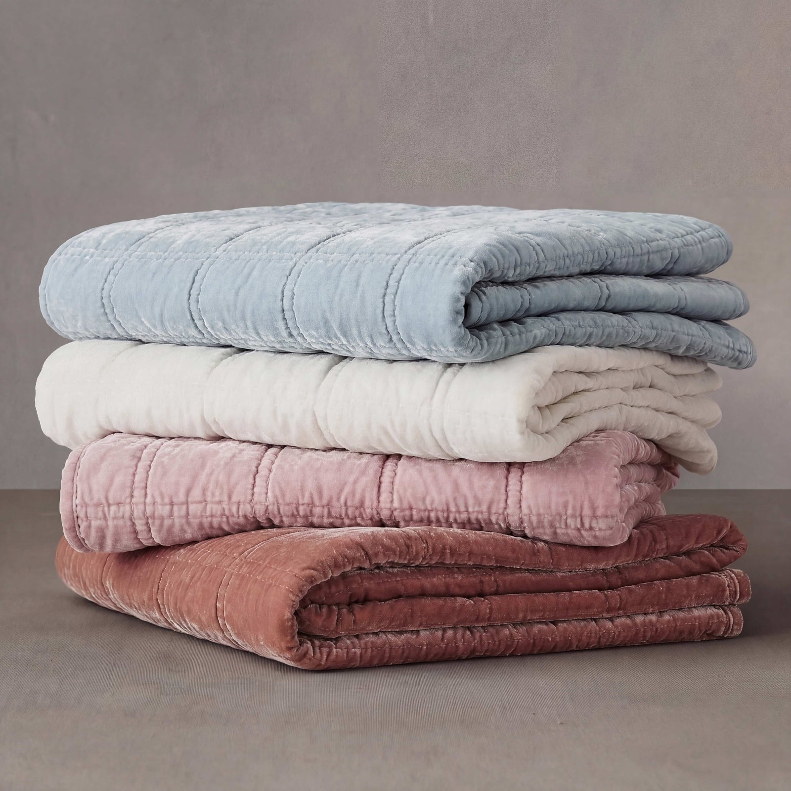 A layered stack of Stella faux silk velvet throws